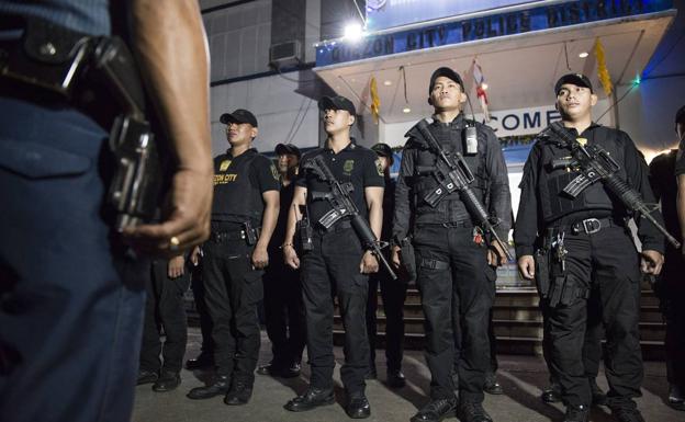 Imagen principal - Zafarrancho de combate. Policías de la comisaría de Batasan se preparan para desplegarse por la ciudad. En las fotos de abajo, escenas de la redada nocturna.