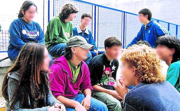 Un grupo de jóvenes conversa en el patio de un colegio.