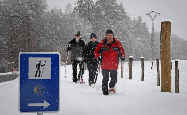 Tres personas caminan con raquetas de nieve en Roncesvalles. 