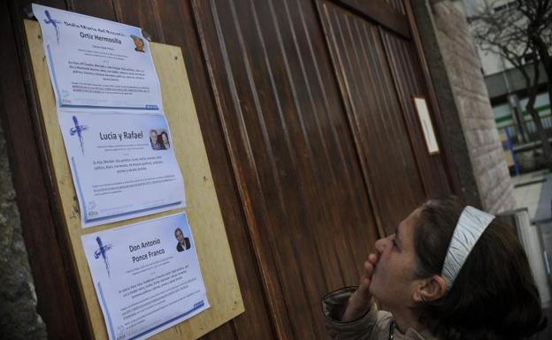 Una vecina observa la esquela de las víctimas