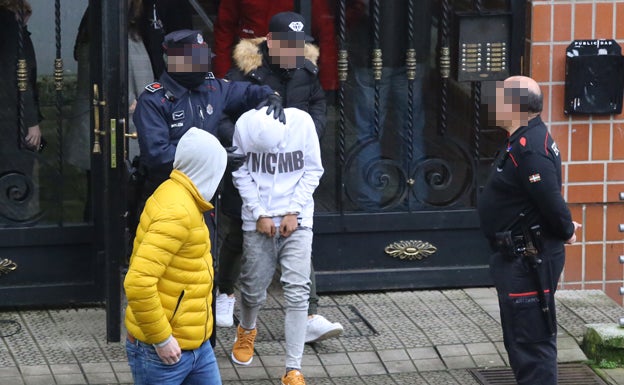 Agentes de la Ertzaintza conducen al menor esposado al finalizar el registro de su domicilio.