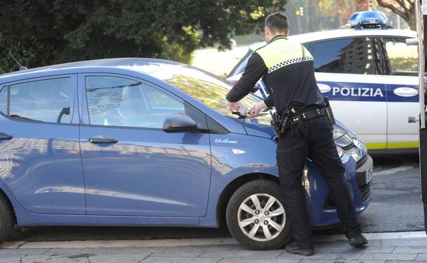 Un Policía Local de Vitoria impone una multa sobre un vehículo.