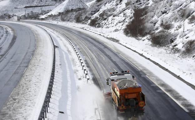 Una quitanieves expande salmuera por una autopista nevada. 