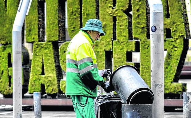Un trabajador de la contrata de limpieza vacía un cubo de la basura en la calle Postas, frente al seto ‘green’.