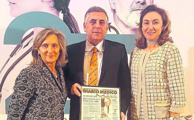 Oteo muestra su título flanqueado por la directora de la revista y la consejera de Salud.