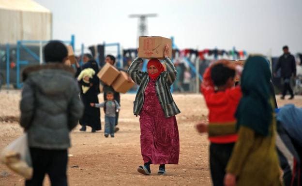 Una mujer siria transporta una caja con ayuda humanitaria en el campamento de refugiados de la localidad de Deir Ezzor.