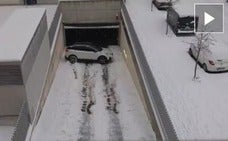 Un conductor trata de sacar su coche de un aparcamiento pero la nieve acumulada en la rampa de acceso le juega una mala pasada. 