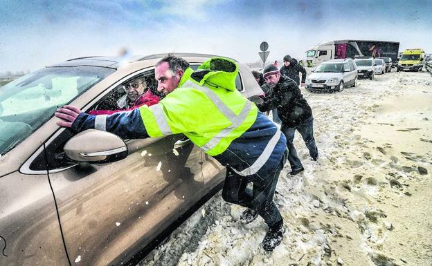 Trabajadores de la Diputación de Álava y voluntarios empujan un coche en la A-1.