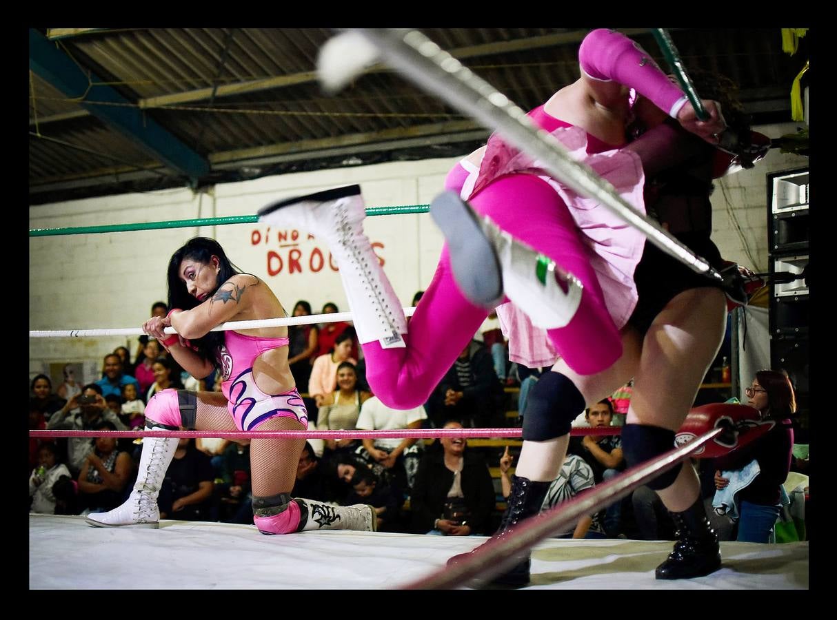 «¡Pinche vieja, vete a la cocina!,» se escucha desde la tribuna mientras la luchadora «Brillo de Luna», con leotardo fucsia salpicado de lentejuelas y botas altas, paraliza con un gancho a Guerrero Nazi, su adversario. A esta deportista mejicana de 42 años, madre de tres hijas, le parece bien que el público masculino la insulte en este combate deportivo-coreográfico. «Significa que estás haciendo bien tu trabajo porque sacan su frustración gritándote en lugar de humillar o golpear a sus esposas cuando vuelvan a casa.« Lucía Urbina, su nombre real, es una de las pocas luchadoras que suben al ring sin máscara para participar en las llamadas peleas mixtas -permitidas hace unos 20 años-, porque representan la “lucha de poder.» “Queremos demostrar al público y a ellos que nosotras también podemos, que no solo ellos y su fuerza, sino nosotras y todas las habilidades que tenemos, pueden sacar adelante un combate y rendirlos.» Siete mexicanas son asesinadas cada día pero sólo un 25% de los casos son investigados como feminicidios, según el Observatorio Ciudadano Nacional del Feminicidio.