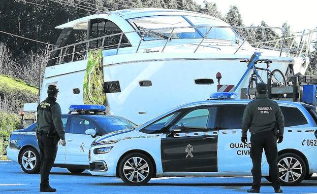 Agentes de la Guardia Civil custodian el cuerpo de la víctima que cuelga del yate, en el parking de transportes especiales de El Haya.