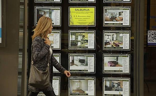 Una mujer pasa frente a una inmobiliaria.