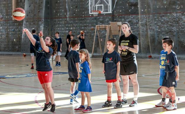 Varios niños esperan a lanzar a canasta durante el campus.