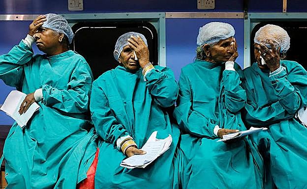 Imagen principal - Cuatro pacientes se cubren un ojo con una gasa después de ser intervenidas de cataratas en el tren hospital.. A continuación, imagen del Lifeline Express, que empezó a rodar en julio de 1991. En su primer viaje llevaba tres vagones. Ahora tiene siete después de que, en diciembre de 2016, recibiera un nuevo obsequio de Indian Railways. Finalmente, los enfermos aguardan a ser atendidos en la sala de espera.
