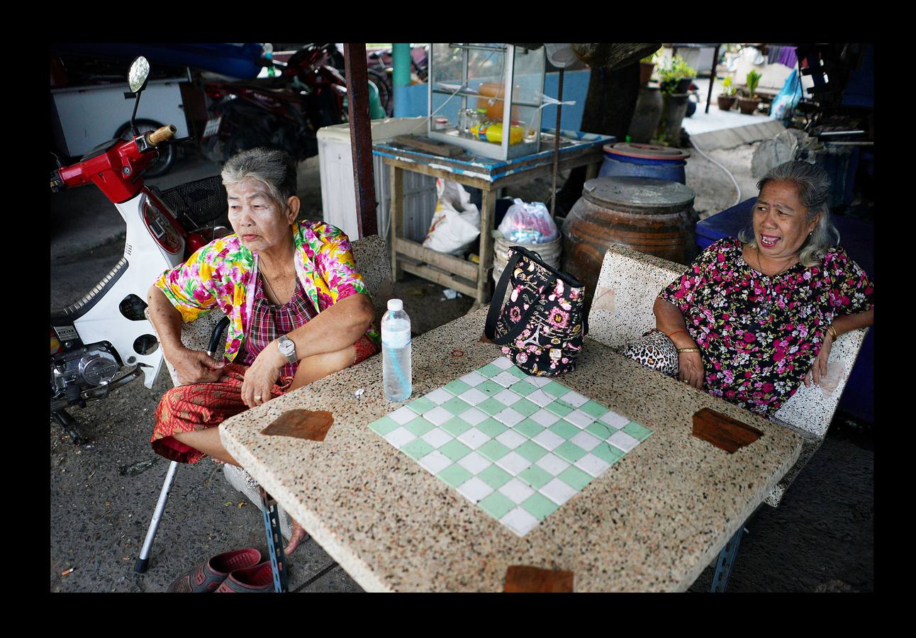 Un grupo de sexagenarias, con uniformes rojos y blancos, sonríen en el autobús que les conduce a la escuela. En Ayutthaya, una provincia de Tailandia, el país que envejece más rápido junto con China, hace no mucho tiempo los ancianos vivían con sus familias y eran cuidados por sus hijos. Pero el progresivo abandono del campo para trabajar en las ciudades ha hecho crecer el número de mayores que viven solos. Escuelas como la de Ayutthaya, ubicada 80 kilómetros al norte de Bangkok, que ofrecen clases semanales durante tres meses, son la manera como el gobierno proporciona alivio a la envejecida población contra el estrés de vivir solos.