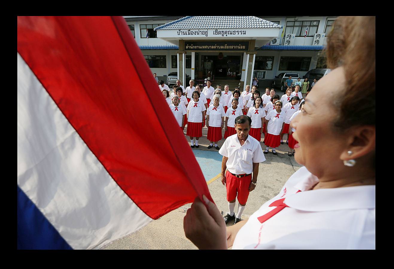 Un grupo de sexagenarias, con uniformes rojos y blancos, sonríen en el autobús que les conduce a la escuela. En Ayutthaya, una provincia de Tailandia, el país que envejece más rápido junto con China, hace no mucho tiempo los ancianos vivían con sus familias y eran cuidados por sus hijos. Pero el progresivo abandono del campo para trabajar en las ciudades ha hecho crecer el número de mayores que viven solos. Escuelas como la de Ayutthaya, ubicada 80 kilómetros al norte de Bangkok, que ofrecen clases semanales durante tres meses, son la manera como el gobierno proporciona alivio a la envejecida población contra el estrés de vivir solos.