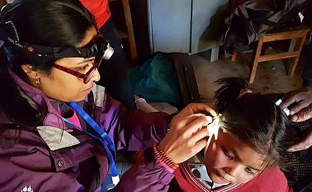 Una doctora mira el oído de una niña nepalí. 