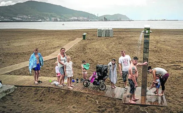 Una familia recoge los bártulos en Ereaga. La lluvia del mediodía espantó a los bañistas. 