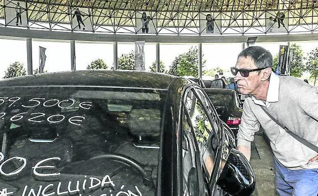 Un hombre se interesa por un coche en la última feria.