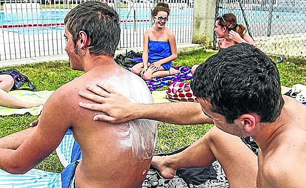 Dos bañistas se protegen con crema solar. 