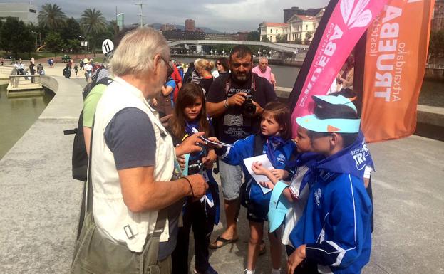 Los alumnos del Colegio Trueba reparten sus guías artesalanes entre los turistas de Bilbao.