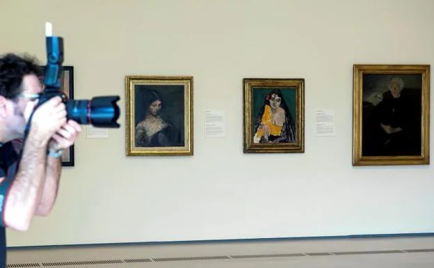Un hombre fotografía las obras de Isidre Nonel (i), Henri Matisse (c) y Francisco Gutiérrez Cossío (d), que forman parte de la nueva sala del Centro Botín.