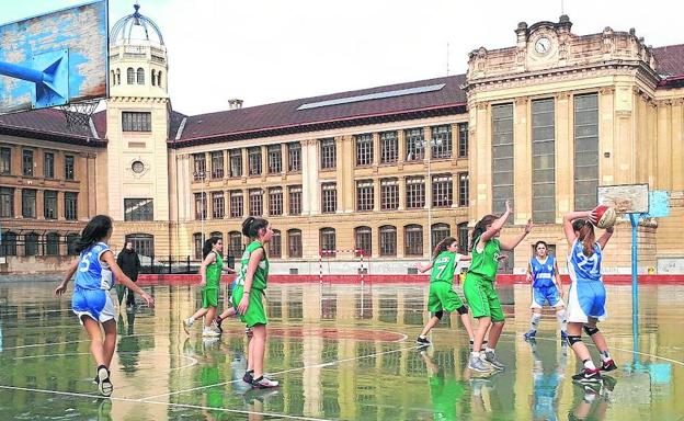 Jugadoras del club Unamuno disputan un partido sobre la cancha mojada. 