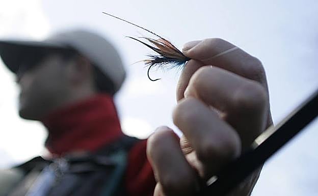 Un pescador muestra la mosca que usa para la pesca.