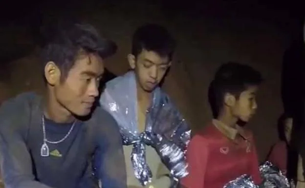 A la izquierda, el entrenador del equipo de fútbol junto a dos de los niños encerrados en la cueva Tham Luang de Tailandia