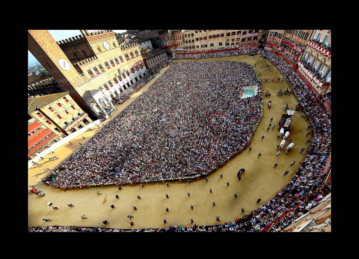 En la Piazza del Campo, en pleno corazón de Siena, en la Toscana, se celebra cada año, en dos ocasiones (las fotografías se tomaron el 2 de julio), la carrera de caballos de origen medieval conocida como «Il Palio.» La ciudad se engalana con estandartes, blasones y guirnaldas para celebrar tres días de alegría durante los cuales, además de participar en las bendiciones de los animales, es posible disfrutar de música y conciertos. En la carrera participan diez caballos, que representan a alguna de las «contradas» o distritos de la ciudad, y han de dar tres vueltas completas a la Piazza del Campo. El primero en terminarlas, con o sin jinete, será el ganador.