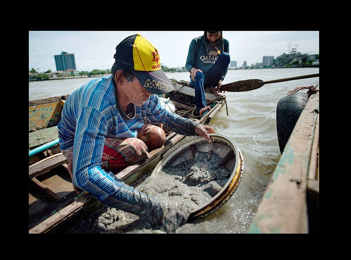 Hace unas semanas, equipos de buzos bien entrenados acapararon el interés mundial por el audaz rescate de 12 niños en una cueva anegada en Tailandia. Pero los buceadores de una pequeña comunidad de ese país, conocida como los «Indiana Jones,» se zambullen a diario hasta a 30 metros con un rudimentario casco de metal, que recuerda a una olla conectada a un tubo de goma, en el turbio cauce del río Chao Phraya, en Bangkok, en busca de tesoros. A veces, consiguen encontrar monedas, joyas o cerámica que pueden vender hasta por el doble del salario mínimo; otras, el hallazgo es macabro: cráneos y esqueletos sobre el lecho del río. Siempre a oscuras.