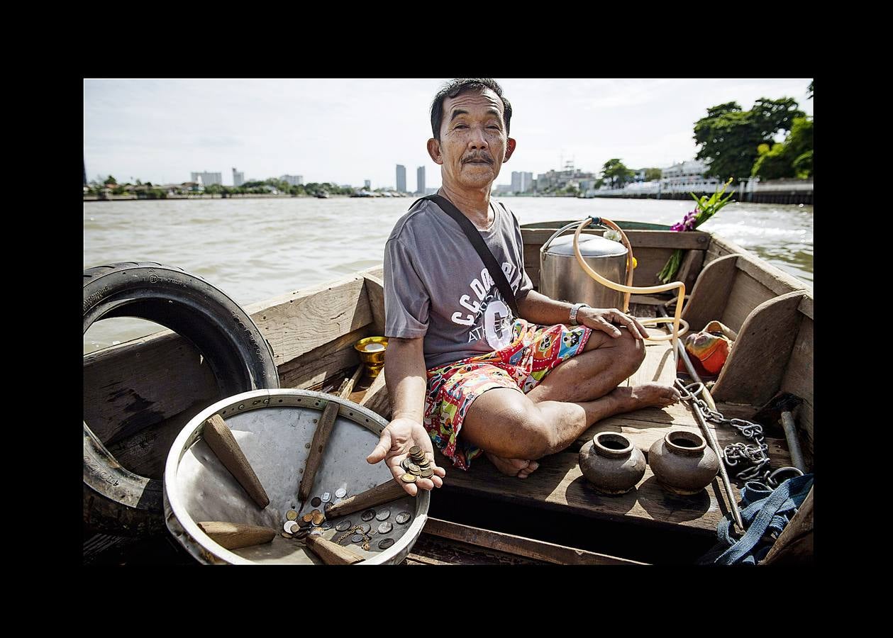 Hace unas semanas, equipos de buzos bien entrenados acapararon el interés mundial por el audaz rescate de 12 niños en una cueva anegada en Tailandia. Pero los buceadores de una pequeña comunidad de ese país, conocida como los «Indiana Jones,» se zambullen a diario hasta a 30 metros con un rudimentario casco de metal, que recuerda a una olla conectada a un tubo de goma, en el turbio cauce del río Chao Phraya, en Bangkok, en busca de tesoros. A veces, consiguen encontrar monedas, joyas o cerámica que pueden vender hasta por el doble del salario mínimo; otras, el hallazgo es macabro: cráneos y esqueletos sobre el lecho del río. Siempre a oscuras.