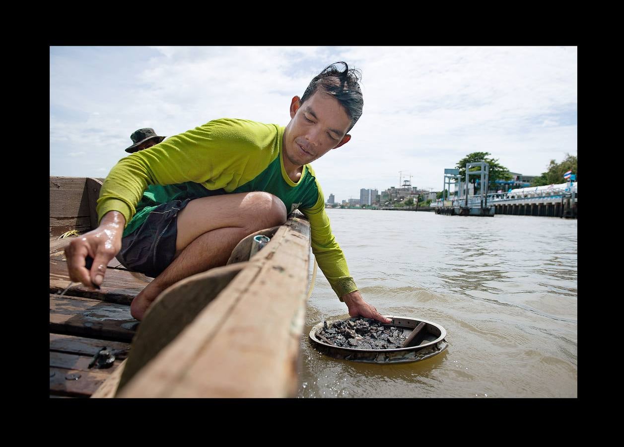 Hace unas semanas, equipos de buzos bien entrenados acapararon el interés mundial por el audaz rescate de 12 niños en una cueva anegada en Tailandia. Pero los buceadores de una pequeña comunidad de ese país, conocida como los «Indiana Jones,» se zambullen a diario hasta a 30 metros con un rudimentario casco de metal, que recuerda a una olla conectada a un tubo de goma, en el turbio cauce del río Chao Phraya, en Bangkok, en busca de tesoros. A veces, consiguen encontrar monedas, joyas o cerámica que pueden vender hasta por el doble del salario mínimo; otras, el hallazgo es macabro: cráneos y esqueletos sobre el lecho del río. Siempre a oscuras.
