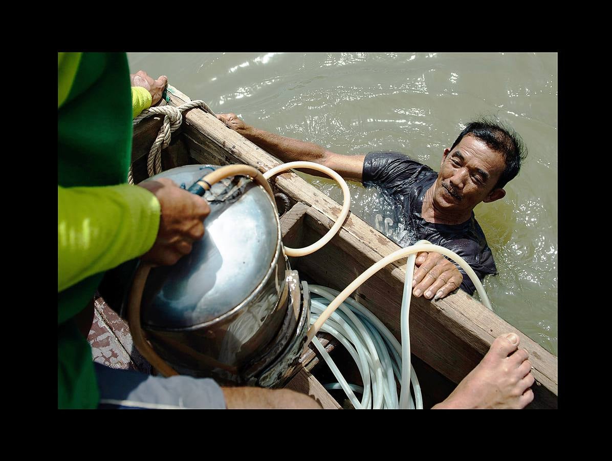 Hace unas semanas, equipos de buzos bien entrenados acapararon el interés mundial por el audaz rescate de 12 niños en una cueva anegada en Tailandia. Pero los buceadores de una pequeña comunidad de ese país, conocida como los «Indiana Jones,» se zambullen a diario hasta a 30 metros con un rudimentario casco de metal, que recuerda a una olla conectada a un tubo de goma, en el turbio cauce del río Chao Phraya, en Bangkok, en busca de tesoros. A veces, consiguen encontrar monedas, joyas o cerámica que pueden vender hasta por el doble del salario mínimo; otras, el hallazgo es macabro: cráneos y esqueletos sobre el lecho del río. Siempre a oscuras.