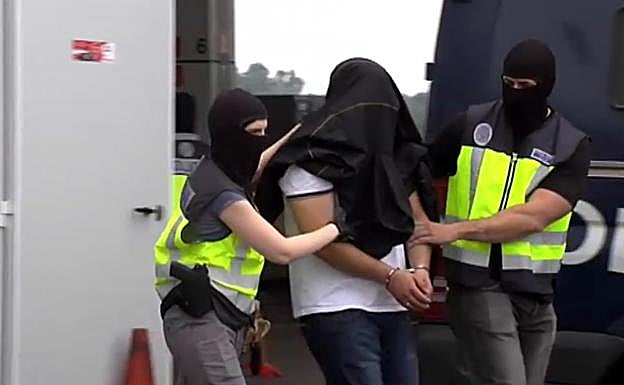 Dos agentes de la Policía Nacional trasladan al detenido a un furgón. 