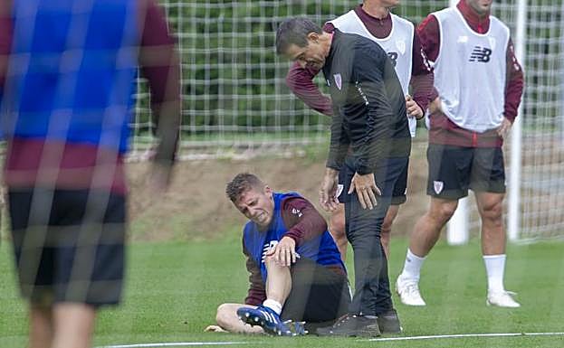 Muniain se duele sobre el césped ante la mirada de Paco Angulo. 