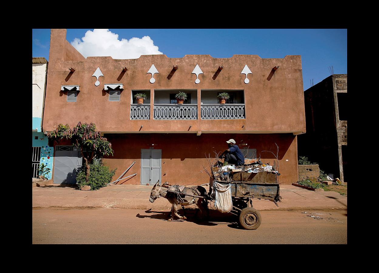 En Bamako, la capital de Mali, los carros tirados por jóvenes como Arouna Diabate (fumando un cigarrillo) y su hermano Salif (con camiseta del Real Madrid), tienen un importante papel en la lucha contra los desechos de la ciudad. Cada mañana, antes del amanecer, los Diabate sujetan el carro a su burro y comienzan las rondas de puerta en puerta para recoger la basura doméstica, que entregan en una estación local de residuos por un salario mensual de 35 dólares. Mali es uno de los países más pobres del mundo y las autoridades tratan de proporcionar servicios adecuados para combatir la proliferación de vertederos informales. La población de Bamako se cuadruplicó desde la década de 1970 hasta alcanzar casi 2 millones de habitantes en 2009.