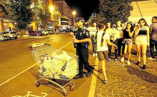 Un agente deposita en un carro de la compra las botellas de alcohol requisadas a los adolescentes. 