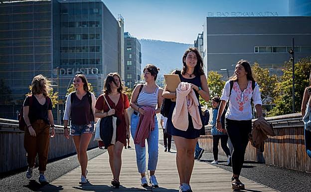 Jóvenes universitarias pasean por el puente Pedro Arrupe. Al fondo, instalaciones de la UPV/EHU y Deusto 