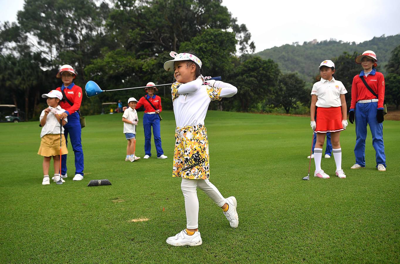 La Asociación China de Golf tenía 400 jugadores juveniles registrados en 2013, el año pasado eran 35.000 y se espera que en un lustro la cifra ronde los 100.000. Lai Runci, de 6 años, y Lai Yiyan, de 9 (protagonistas en la mayoría de las fotos), participan en un torneo para niños en Dragon Lake Golf Club en, Guangzhou. Ambos representan al ejército de jóvenes golfistas de China y el interés creciente del país por un juego que estuvo prohibido bajo el mandato de Mao Zedong porque era «para millonarios...»