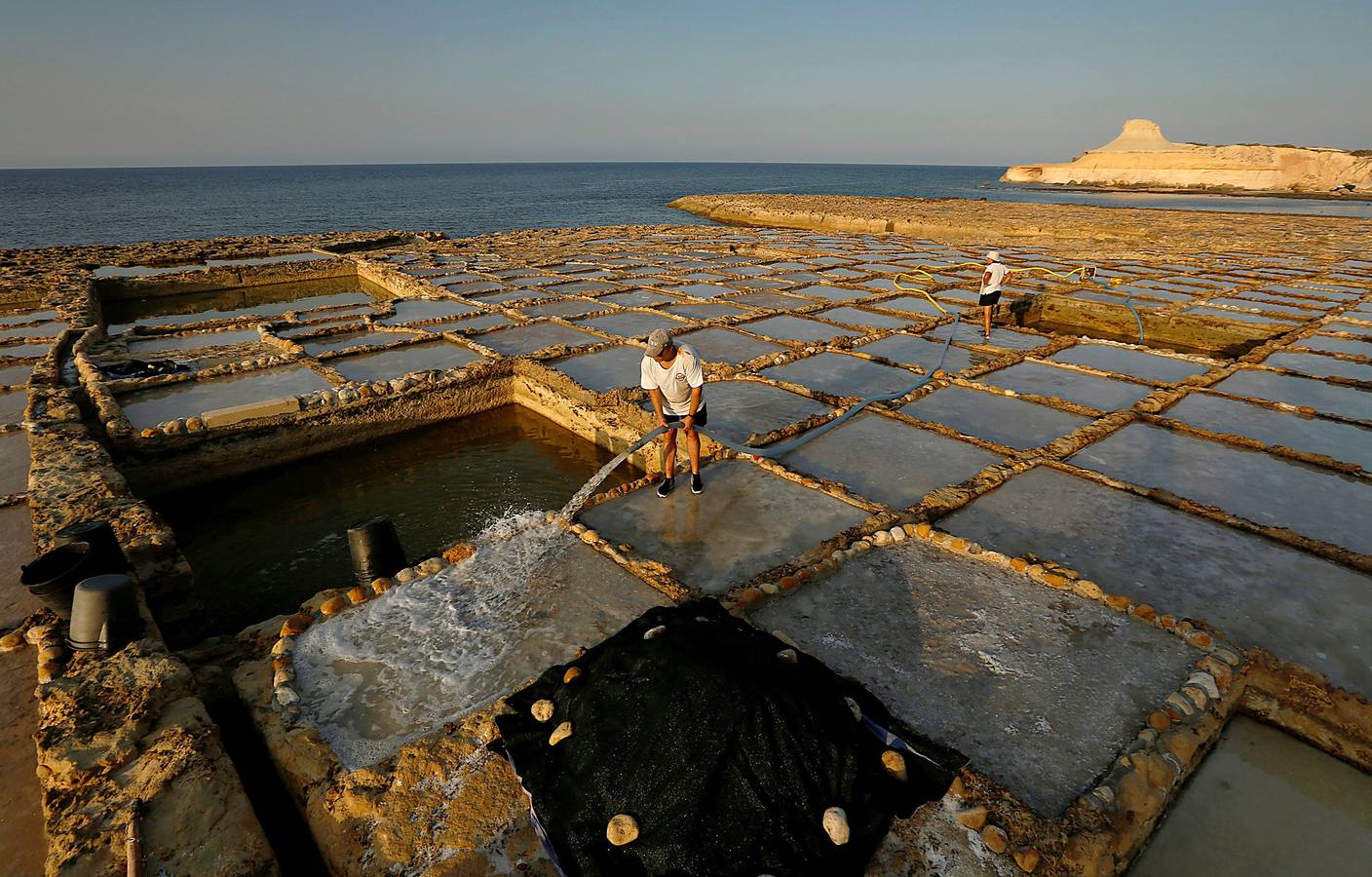 Zebbug, en la isla de Gozo, en Malta, es una pequeña localidad famosa por sus finos encajes; por los olivos, que le dieron el nombre, y por la sal. A ella se dedican numerosos habitantes que, como Josephine Xuereb y Rosa Cini (en las fotos), la tratan y almacenan en salinas excavadas en roca y en paneles de evaporación, que se extienden a lo largo de la costa, de la misma forma que hicieron otras generaciones desde hace más de 350 años. 