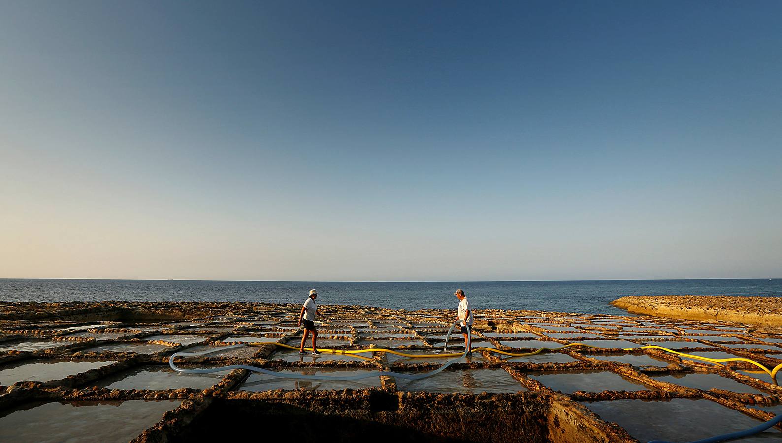 Zebbug, en la isla de Gozo, en Malta, es una pequeña localidad famosa por sus finos encajes; por los olivos, que le dieron el nombre, y por la sal. A ella se dedican numerosos habitantes que, como Josephine Xuereb y Rosa Cini (en las fotos), la tratan y almacenan en salinas excavadas en roca y en paneles de evaporación, que se extienden a lo largo de la costa, de la misma forma que hicieron otras generaciones desde hace más de 350 años. 