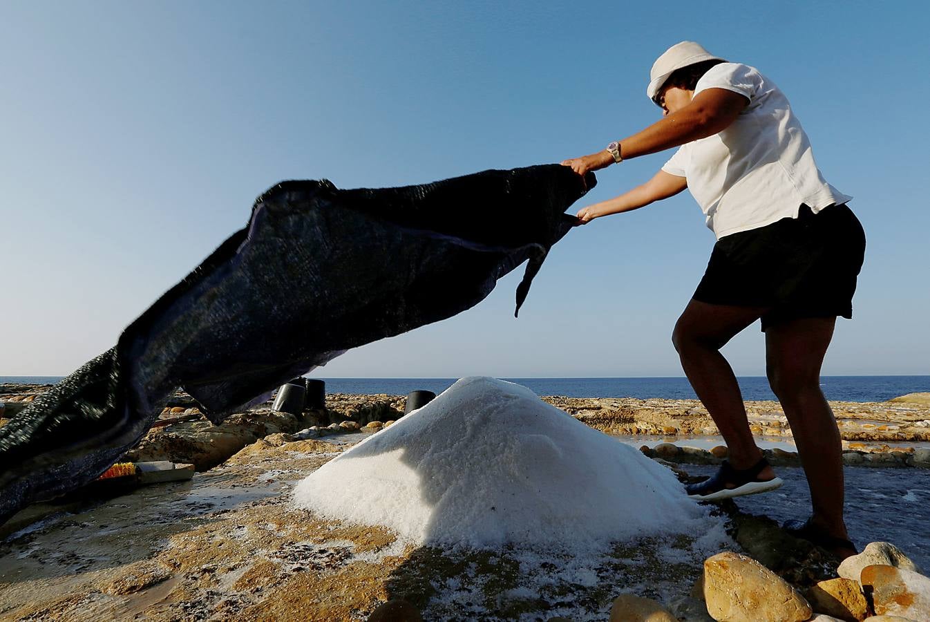 Zebbug, en la isla de Gozo, en Malta, es una pequeña localidad famosa por sus finos encajes; por los olivos, que le dieron el nombre, y por la sal. A ella se dedican numerosos habitantes que, como Josephine Xuereb y Rosa Cini (en las fotos), la tratan y almacenan en salinas excavadas en roca y en paneles de evaporación, que se extienden a lo largo de la costa, de la misma forma que hicieron otras generaciones desde hace más de 350 años. 