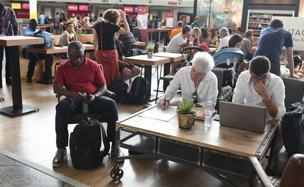 Varios viajeros esperan en la terminal de salida de Loiu. 