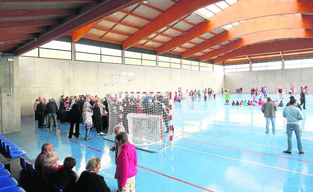 Los mayores disfrutan de un aperitivo en el polideportivo mientras los niños jugaban.