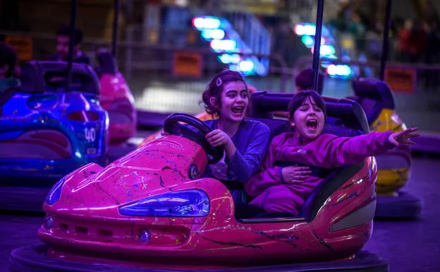 Dos niñas se divierten en los autos de choque.