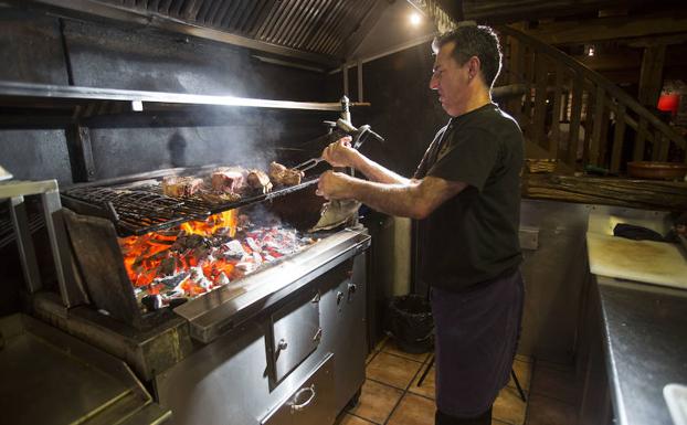 El parrillero trabaja la carne a la brasa.