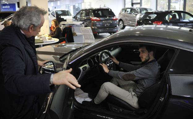 Dos hombres observan un automóvil a la venta en un concesionario.