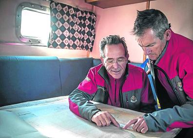 Imagen secundaria 1 - Tito López es el patrón de la embarcación de rescate 'Itsas Zain'. En la imagen de arriba a la izquierda, dirige la maniobra para salir del Abra. Abajo, en el camarote, consultando la carta de navegación correspondiente al fondeadero de Matxitxako. Abajo, Josean Sánchez, mecánico, lleva nueve años asignadoa la embarcación. Observael panel de instrumentos mientras al otro lado del portillo se dibuja la plataforma de gas 'Gaviota'.