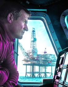 Imagen secundaria 2 - Tito López es el patrón de la embarcación de rescate 'Itsas Zain'. En la imagen de arriba a la izquierda, dirige la maniobra para salir del Abra. Abajo, en el camarote, consultando la carta de navegación correspondiente al fondeadero de Matxitxako. Abajo, Josean Sánchez, mecánico, lleva nueve años asignadoa la embarcación. Observael panel de instrumentos mientras al otro lado del portillo se dibuja la plataforma de gas 'Gaviota'.