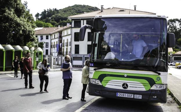 Usuarios cruzan la carretera para subir al autobús en Lekeitio.